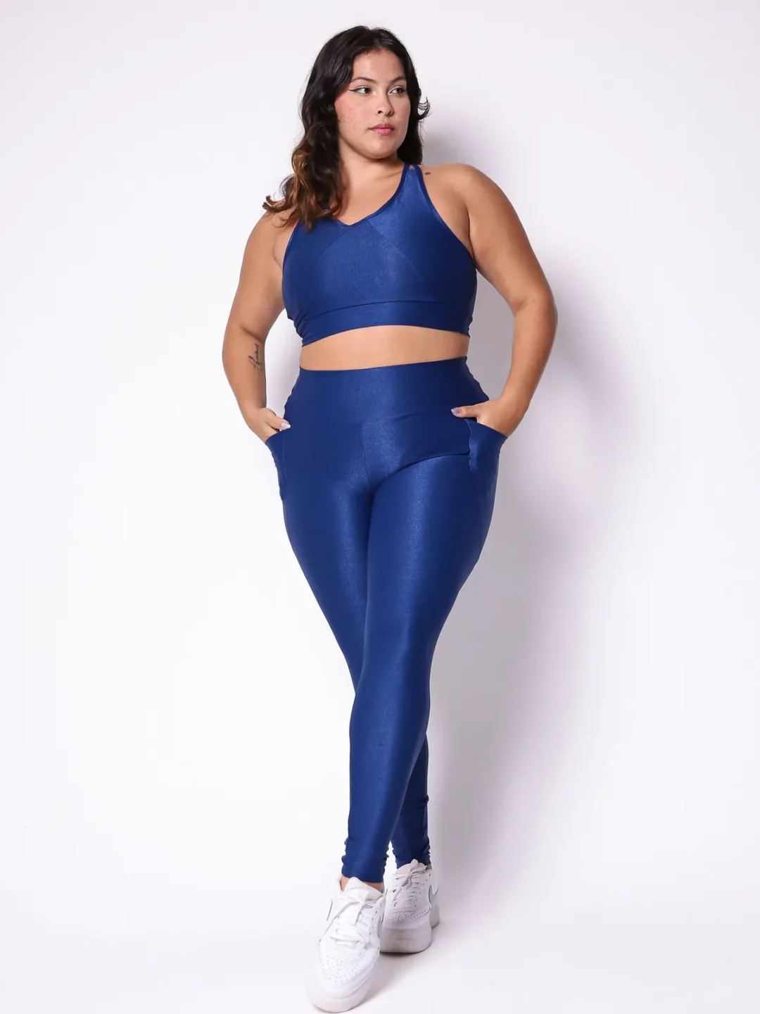 Modelo plus size vestindo o conjunto de Legging de Bolso e Top Clara feito em tecido aveludado de compressão, na cor azul night blue