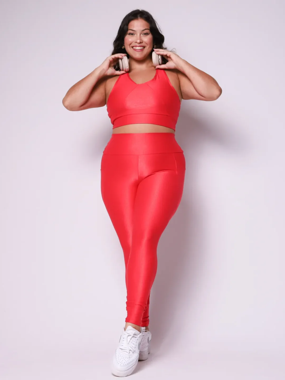 Modelo plus size vestindo o conjunto de Legging de Bolso e Top Clara feito em tecido aveludado de compressão, na cor vermelho