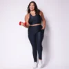 Modelo plus size vestindo o conjunto de Legging Bolso e Top Clara feito em tecido Aveludado de compressão, na cor preta