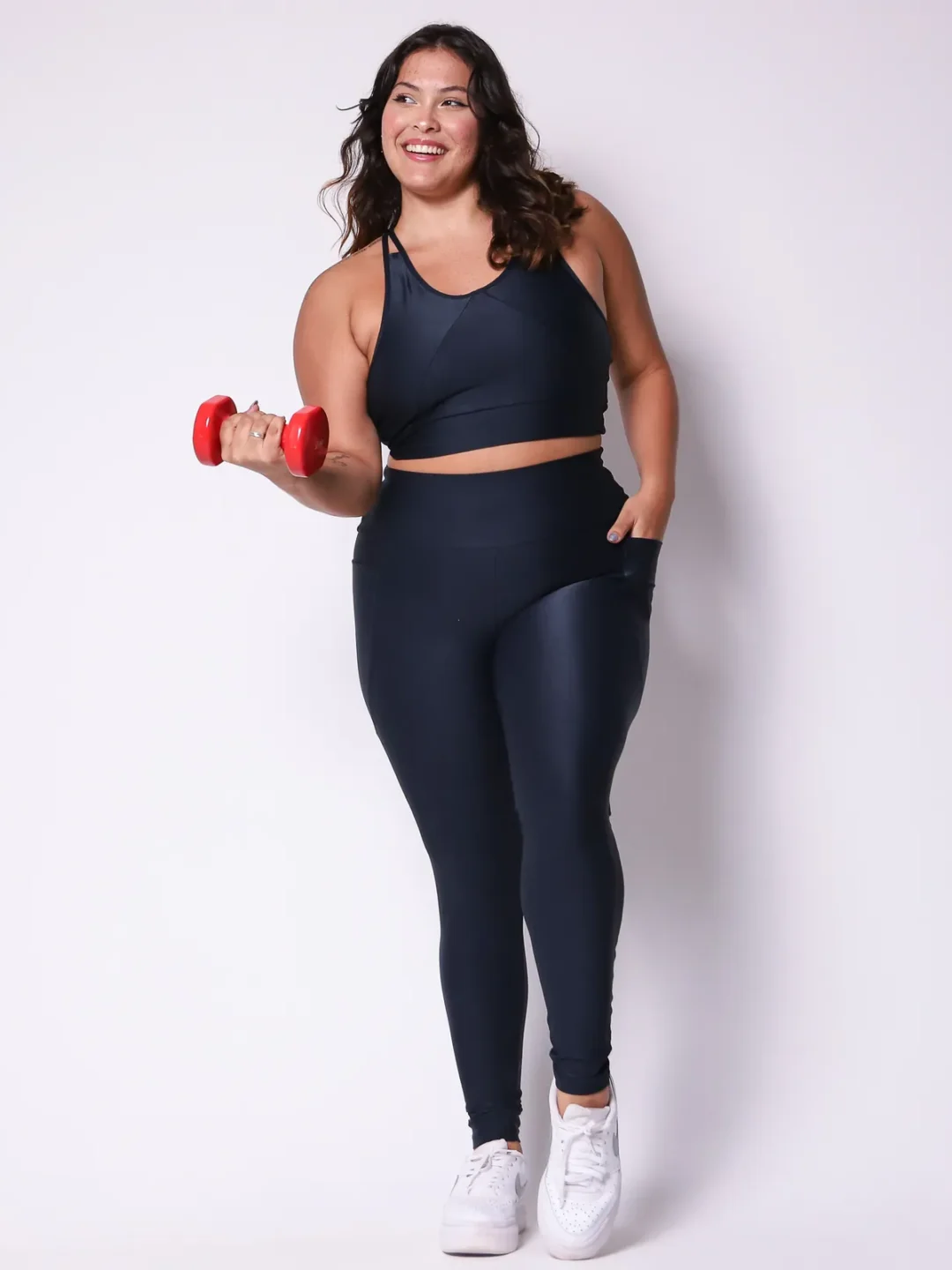 Modelo plus size vestindo o conjunto de Legging Bolso e Top Clara feito em tecido Aveludado de compressão, na cor preta