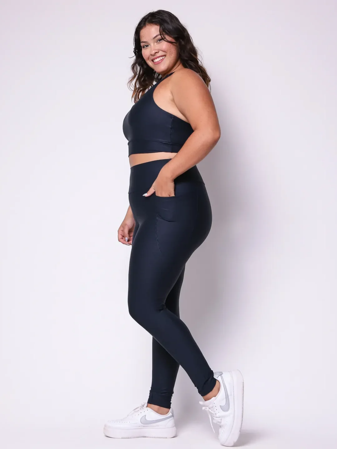 Modelo plus size vestindo o conjunto de Legging Bolso e Top Clara feito em tecido Aveludado de compressão, na cor preta