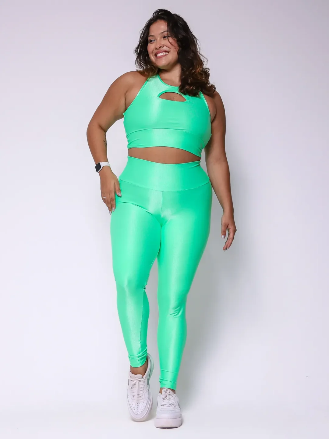 Modelo plus size vestindo o conjunto de Legging Clássica e Top Valquíria feito em tecido Aveludado de compressão, na cor verde tropical